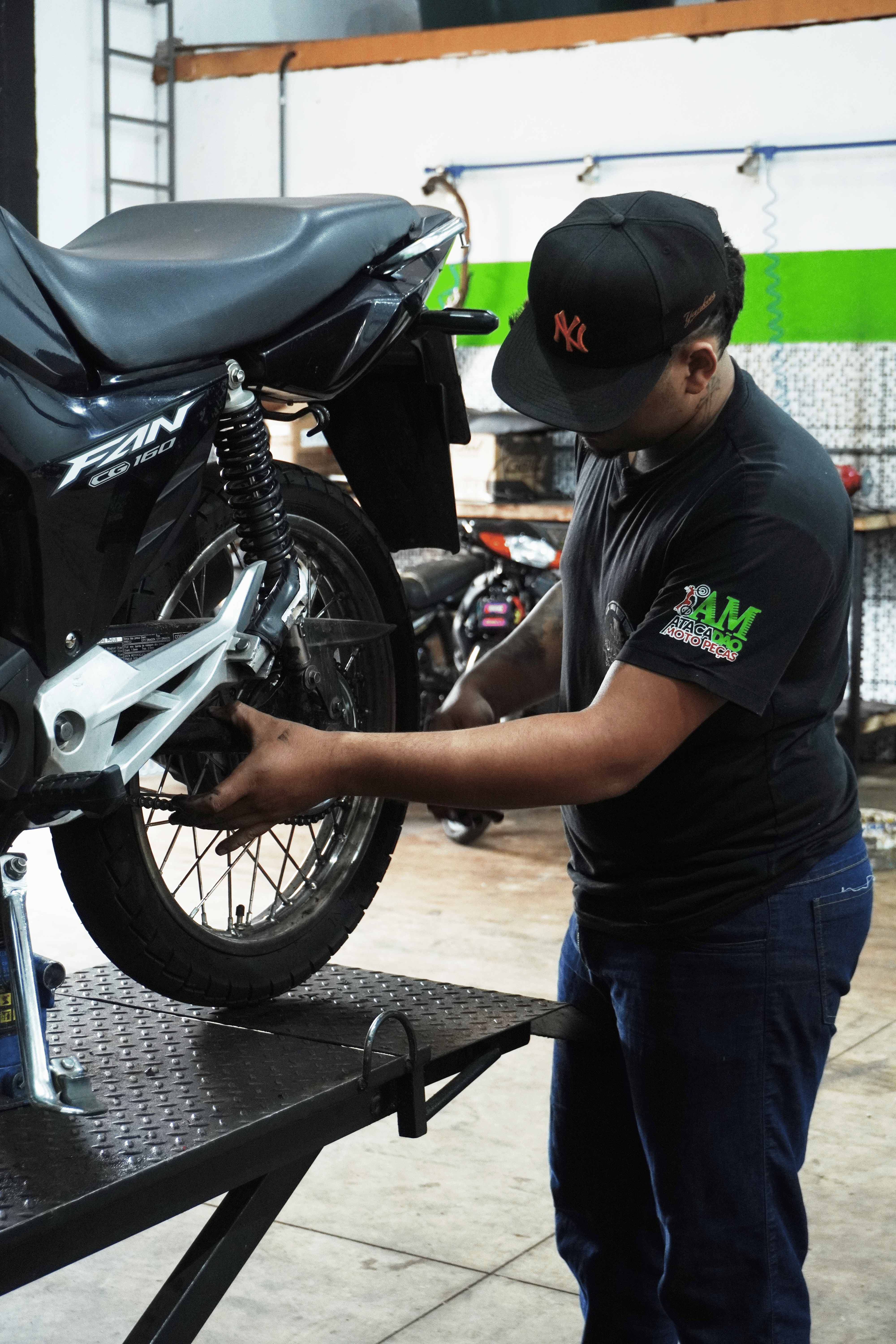 Mecânico revisando a roda traseira de uma motocicleta na oficina